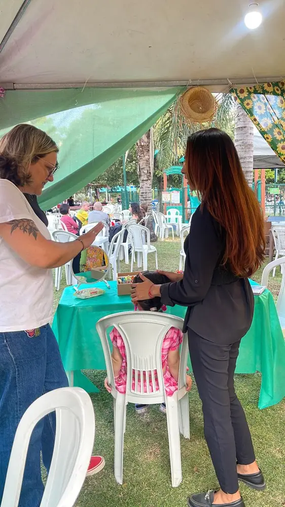 Criança sendo penteada em mesa de atividades na tenda
